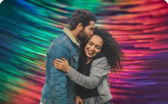 A couple embracing against a colourful abstract backdrop